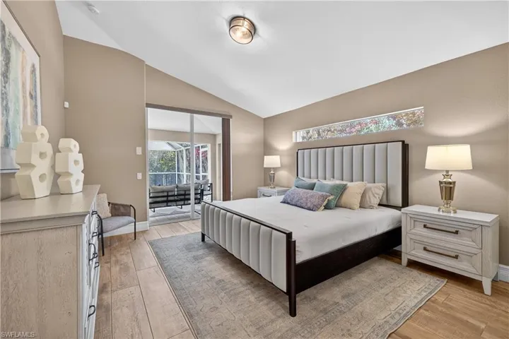 Bedroom featuring access to outside, light wood-style flooring, and lofted ceiling