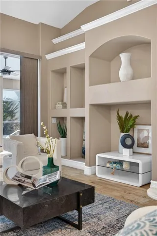 Living area featuring built in shelves, wood finished floors, and a ceiling fan