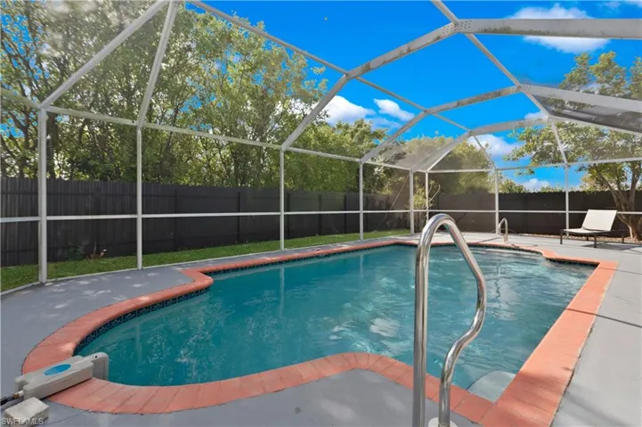 View of pool with a fenced backyard, a lanai, a sunroom, and patio surround