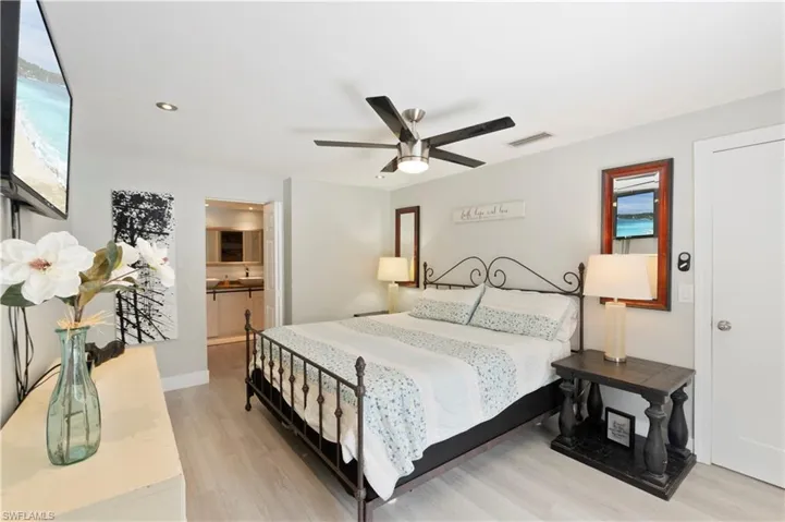 Bedroom with light wood-style floors, a ceiling fan, ensuite bath, and recessed lighting