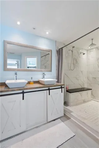 Full bath with a marble finish shower and double vanity