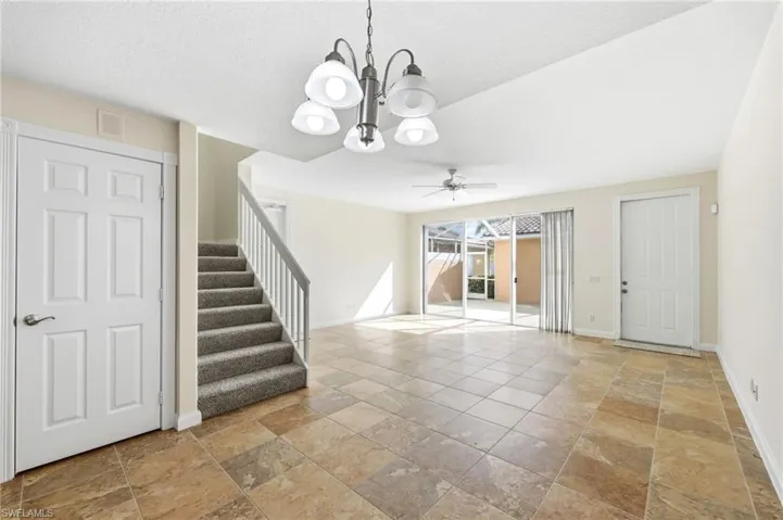 dining area featuring a ceiling fan, stone tile flooring, and suspended lighting
