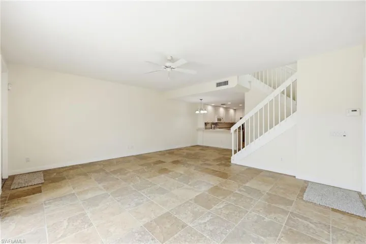 Unfurnished living room featuring a ceiling fan and light stone finish flooring