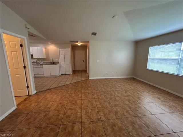 Unfurnished living room featuring tile patterned flooring and vaulted ceiling