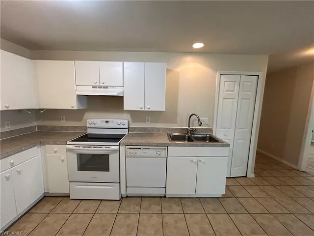 Kitchen with white appliances, white cabinetry, light tile patterned flooring, under cabinet range hood, and recessed lighting
