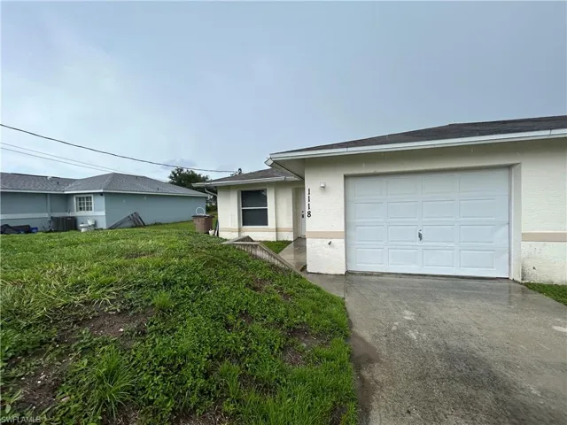 Single story home featuring a garage, stucco siding, concrete driveway, and a front lawn