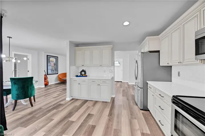 Kitchen featuring baseboards, electric range oven, light countertops, light wood-type flooring, and decorative backsplash