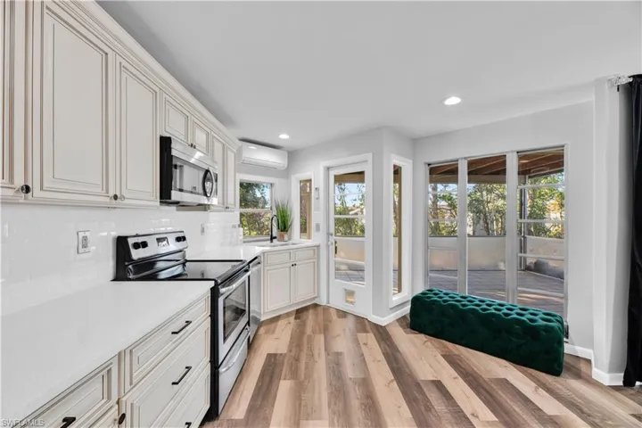 Kitchen with a sink, light wood-style floors, a wall unit AC, and stainless steel appliances
