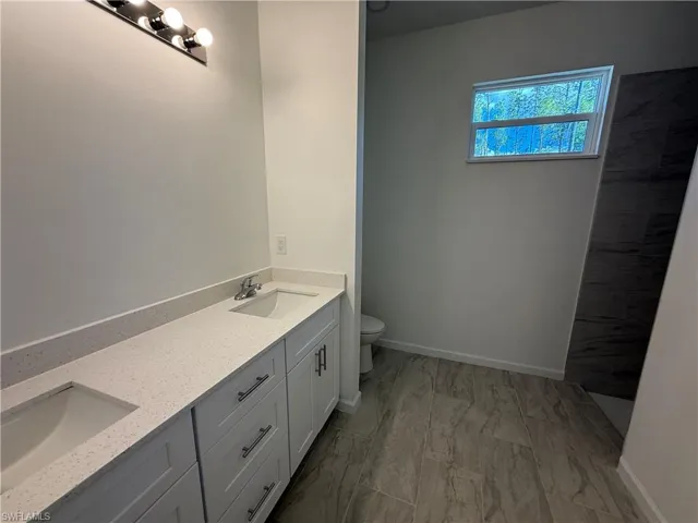 Full bath featuring double vanity and tiled shower