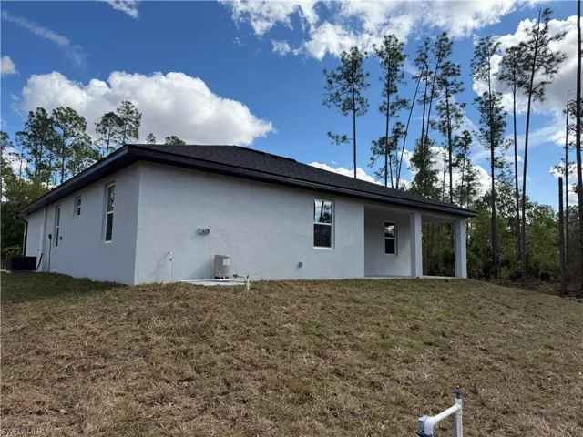 Rear view of property featuring stucco siding, a lawn, and a patio
