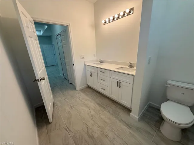 Full bathroom featuring double vanity and toilet