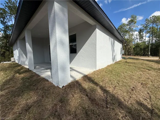 View of side of home with a lawn, a patio area, and stucco siding