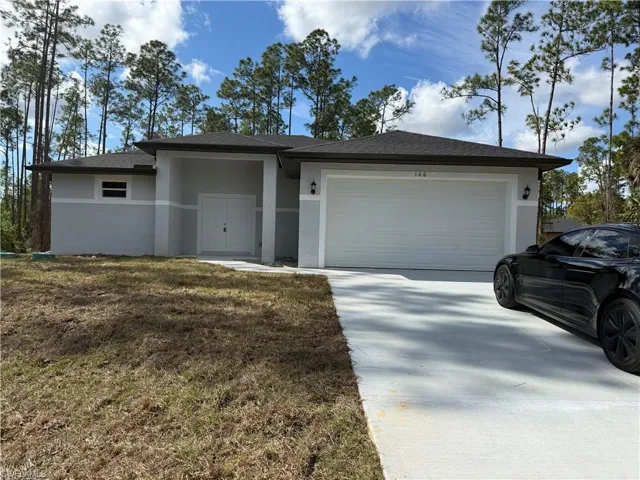 View of front of house with stucco siding, driveway, an attached garage, and a front lawn