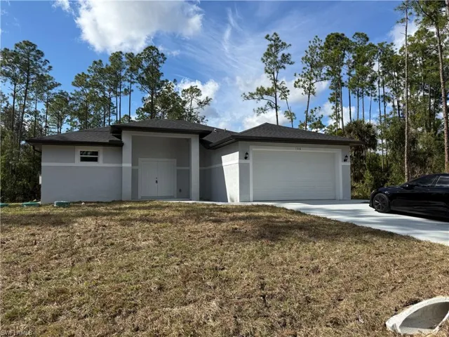 Prairie-style house featuring stucco siding, a front lawn, a garage, and concrete driveway