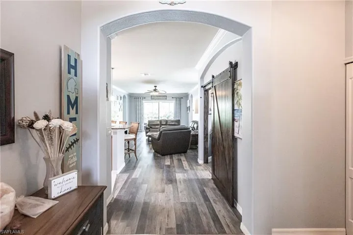 Hall with a barn door, dark hardwood / wood-style flooring, and crown molding