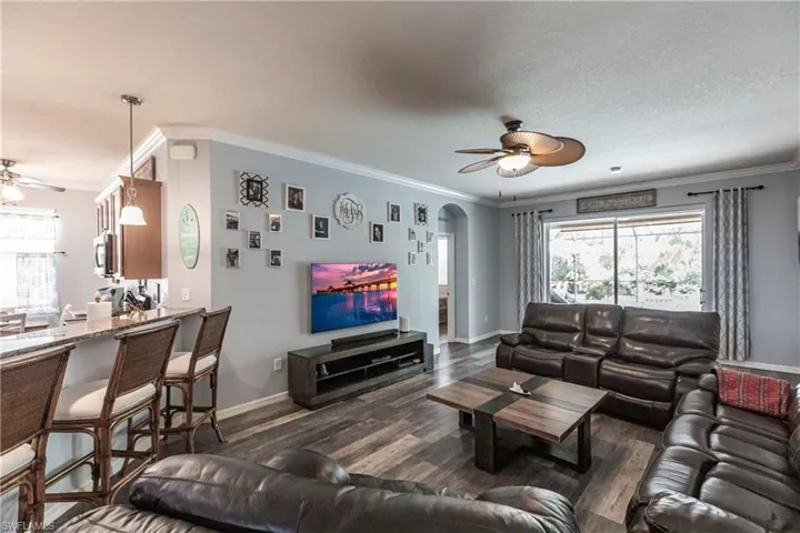 Living room with ornamental molding, dark hardwood / wood-style floors, ceiling fan, and a textured ceiling