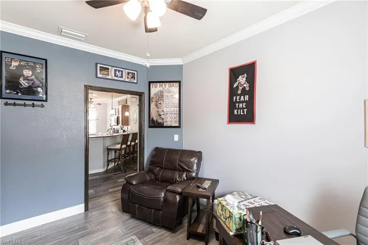 Living area with ceiling fan, hardwood / wood-style flooring, and crown molding