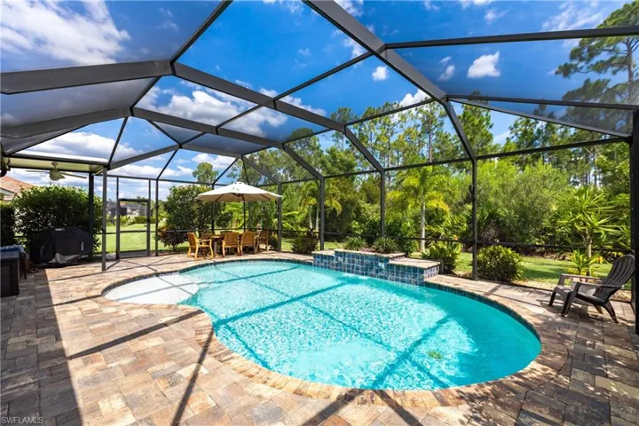 View of swimming pool with a patio, pool water feature, glass enclosure, and grilling area
