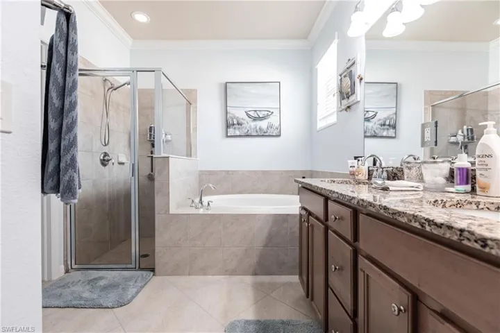 Bathroom featuring vanity with extensive cabinet space, independent shower and bath, tile flooring, and crown molding