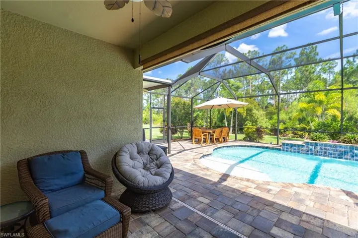 View of pool with a patio area, pool water feature, glass enclosure, and ceiling fan
