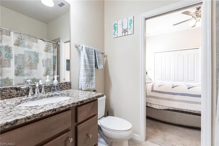 Bathroom featuring tile floors, ceiling fan, toilet, and large vanity