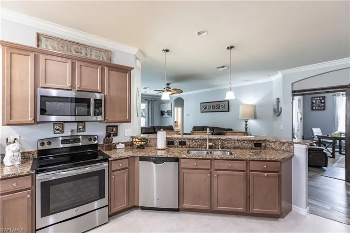 Kitchen with decorative light fixtures, light hardwood / wood-style flooring, ceiling fan, appliances with stainless steel finishes, and sink