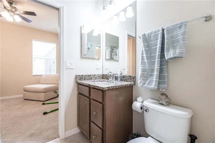 Bathroom featuring vanity, toilet, and ceiling fan