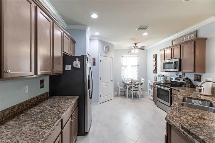 Kitchen with ornamental molding, stainless steel appliances, sink, light tile flooring, and ceiling fan