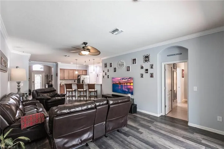 Living room with dark hardwood / wood-style floors, ceiling fan, and ornamental molding