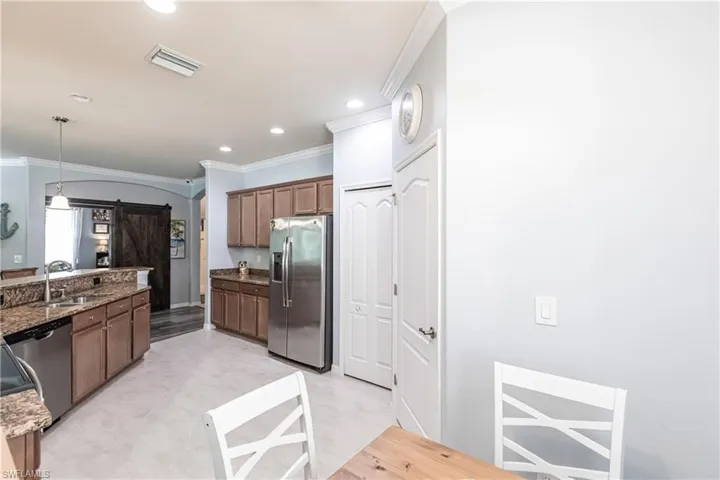 Kitchen with stainless steel appliances, light tile floors, sink, and dark stone countertops