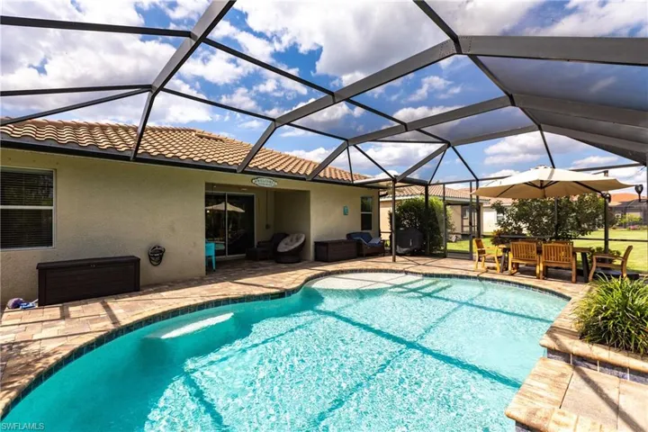 View of pool with outdoor lounge area, a patio, and glass enclosure