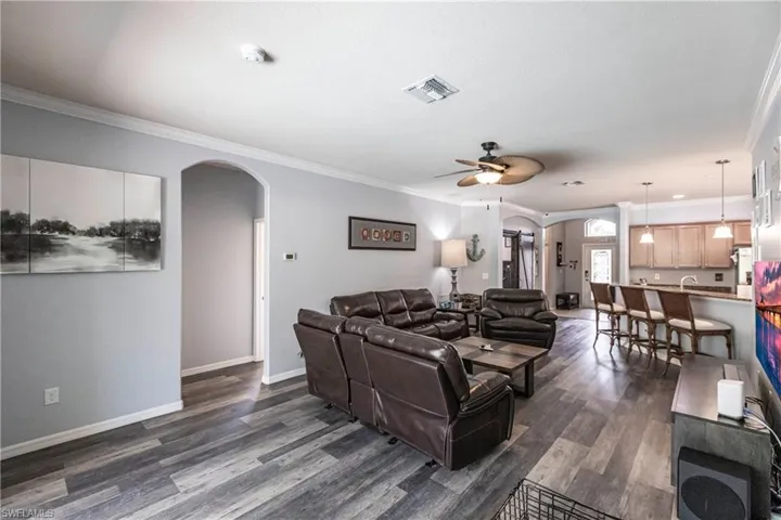 Living room featuring ornamental molding, dark hardwood / wood-style floors, and ceiling fan