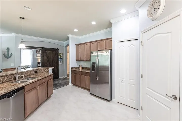 Kitchen with dark stone counters, appliances with stainless steel finishes, decorative light fixtures, sink, and ornamental molding