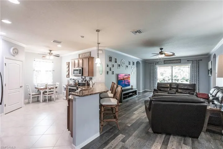 Living room featuring tile floors, ceiling fan, a textured ceiling, and crown molding