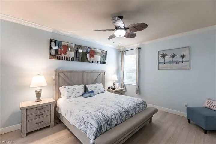 Bedroom featuring ceiling fan, light hardwood / wood-style flooring, and crown molding