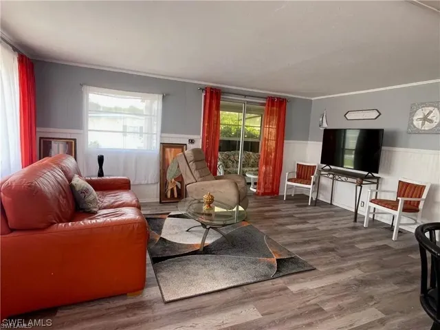 Living area featuring wood-finish flooring, two-tone walls with wainscoting, and large windows with natural light