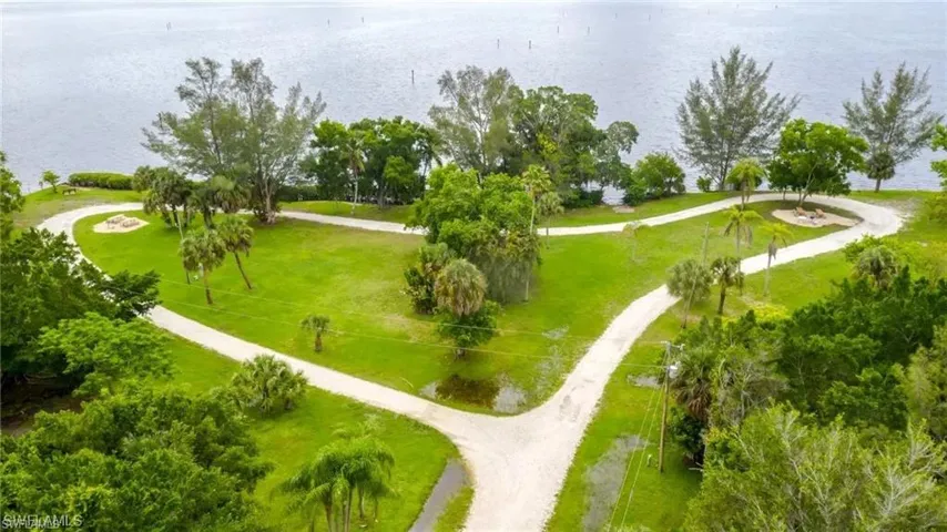 Expansive waterfront property featuring lush green lawns, mature palm trees, and winding pathways leading to the water's edge
