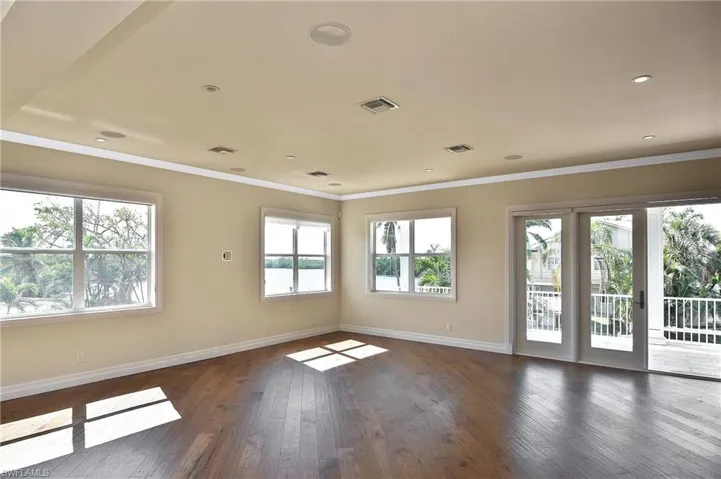 Empty room with ornamental molding and dark wood-type flooring