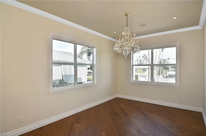Spare room featuring an inviting chandelier, ornamental molding, and dark hardwood / wood-style floors