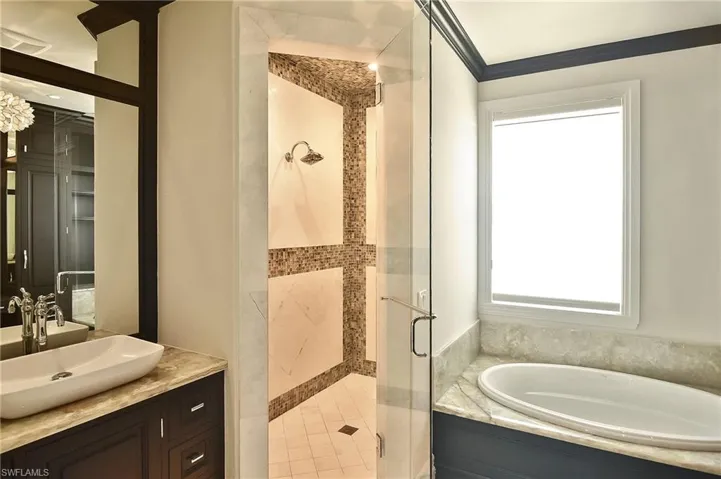 Bathroom featuring crown molding, vanity, and plus walk in shower