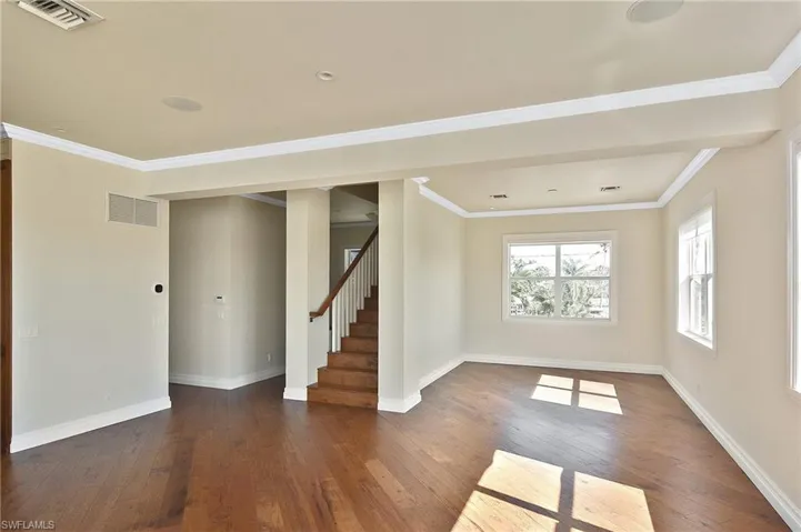 Spare room featuring crown molding and dark hardwood / wood-style floors
