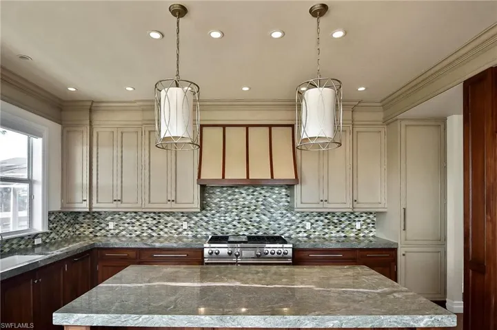 Kitchen featuring a center island, range, light stone countertops, and cream cabinetry