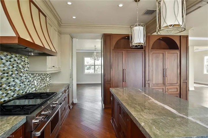 Kitchen featuring premium range hood, ornamental molding, range with two ovens, and stone counters