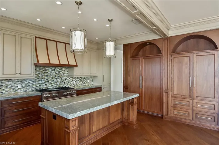 Kitchen with hanging light fixtures, double oven range, cream cabinets, and a large island