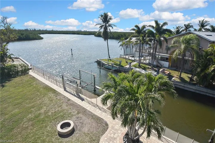 Property view of water featuring a boat dock and an outdoor fire pit
