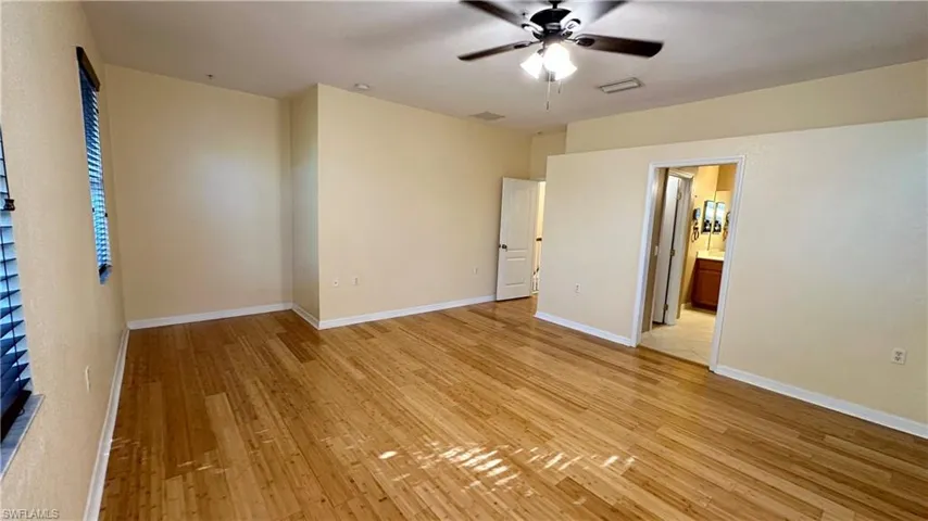 Unfurnished bedroom featuring light wood-type flooring, a ceiling fan, and connected bathroom
