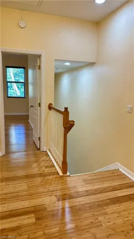 Corridor featuring an upstairs landing, light wood finished floors, and a textured wall