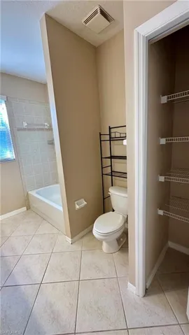 Full bathroom with a bath, a textured ceiling, and light tile patterned floors