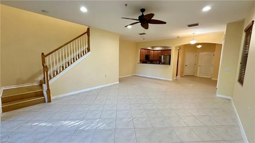 Unfurnished living room with arched walkways, stairs, recessed lighting, ceiling fan, and light tile patterned flooring