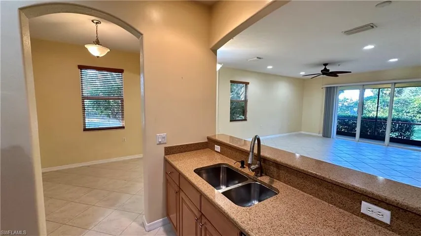 Kitchen with light tile patterned floors, light stone counters, arched walkways, healthy amount of natural light, and recessed lighting